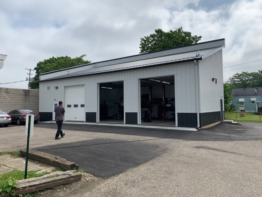 Monoslope pole barn used as an auto repair shop with service bays and steel siding.