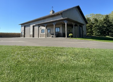 Ultimate man cave garage with steel siding, multiple overhead doors, covered porch, and cupola in Wisconsin