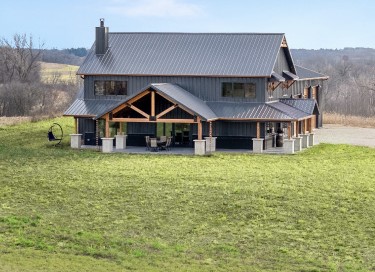 Luxury hunting cabin with timber frame porch, steel roof, wraparound covered porch, and rural setting