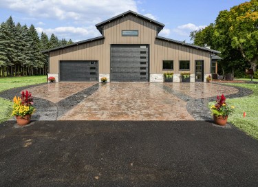 Monitor barndominium with raised center section, steel siding, and large overhead garage doors in Wisconsin