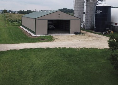Agricultural equipment storage building with steel siding and large sliding door on a farm