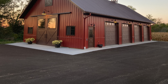 Custom machinery storage building with red steel siding, cupolas and multiple overhead doors