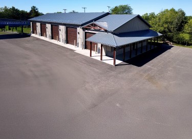 Storage condominiums with steel siding, multiple overhead doors, covered entry, and paved drive lanes in Wisconsin