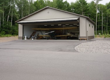 Airport hangar with large bi-fold door open, aircraft inside, and steel siding in Wisconsin