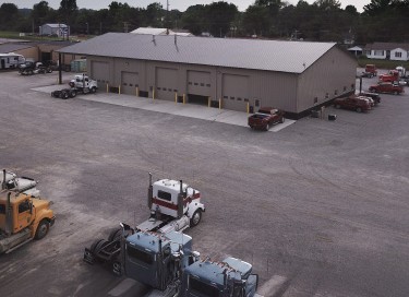 Equipment service building with steel siding, multiple overhead doors, and truck yard at Vaughan Equipment Inc
