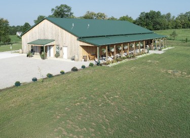 Kentucky wedding venue barn with wood siding, green steel roof, and covered porch in rural setting