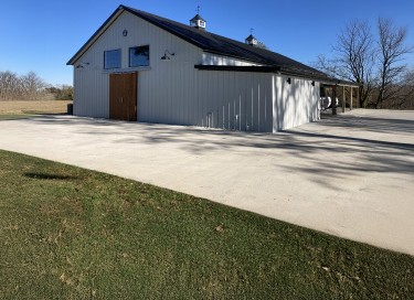 Silo Farms event barn with white steel siding, black roof, cupolas, and large entry doors in rural setting