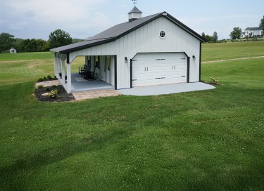 Pole shed with covered porch, white steel siding, overhead garage door, and cupola in Wisconsin