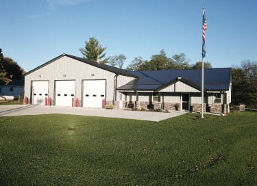Bagdad Fire Department fire station with steel siding, multiple overhead doors, office entrance, and American flag