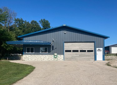 Lake house garage with blue steel siding, overhead garage door, stone wainscot, and residential design in Wisconsin