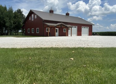Pole barn workshop with red steel siding, dual overhead garage doors, covered porch, and cupolas in Illinois