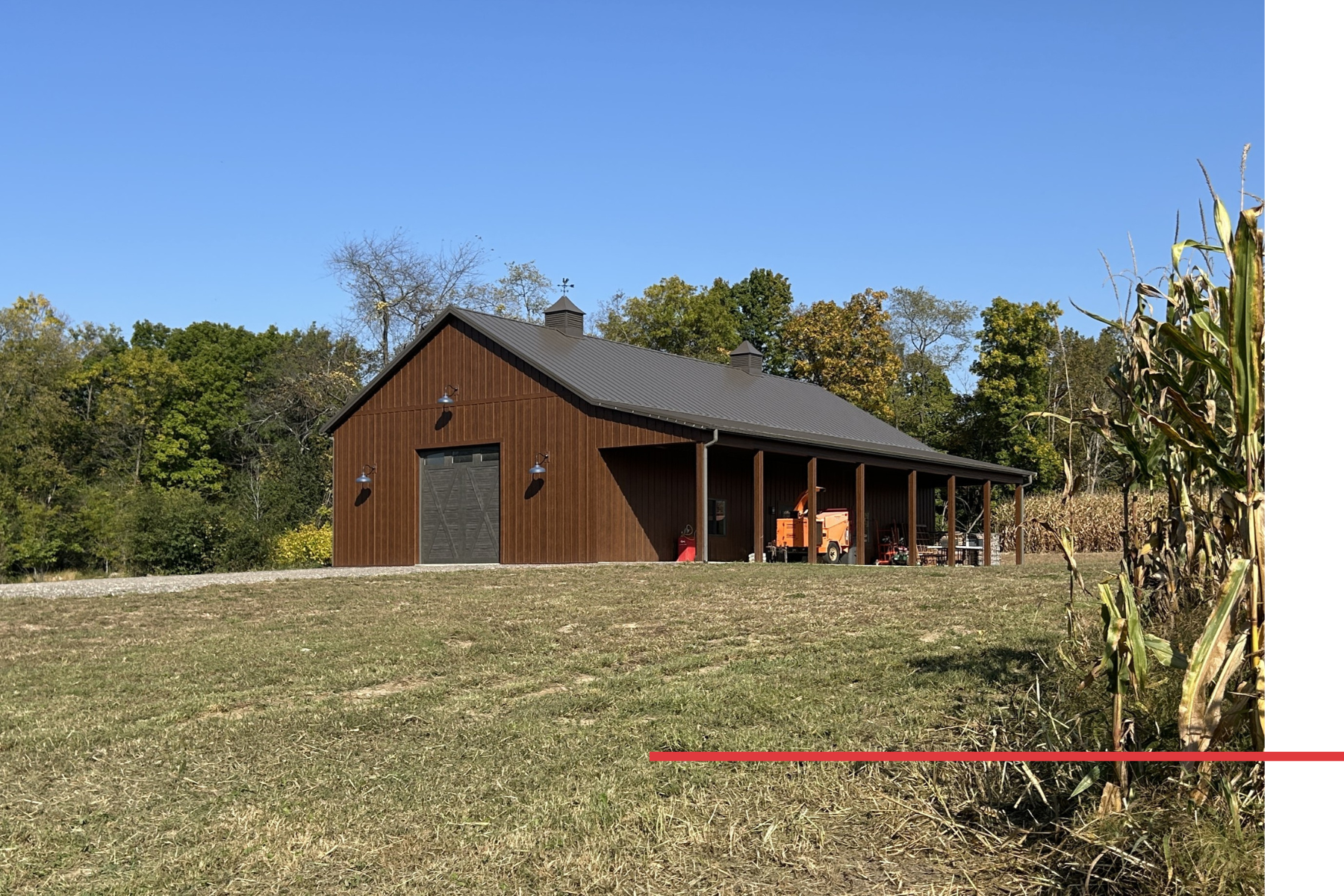 Distant view of a 36' x 72' board and batten pole barn with side porch and twin cupolas