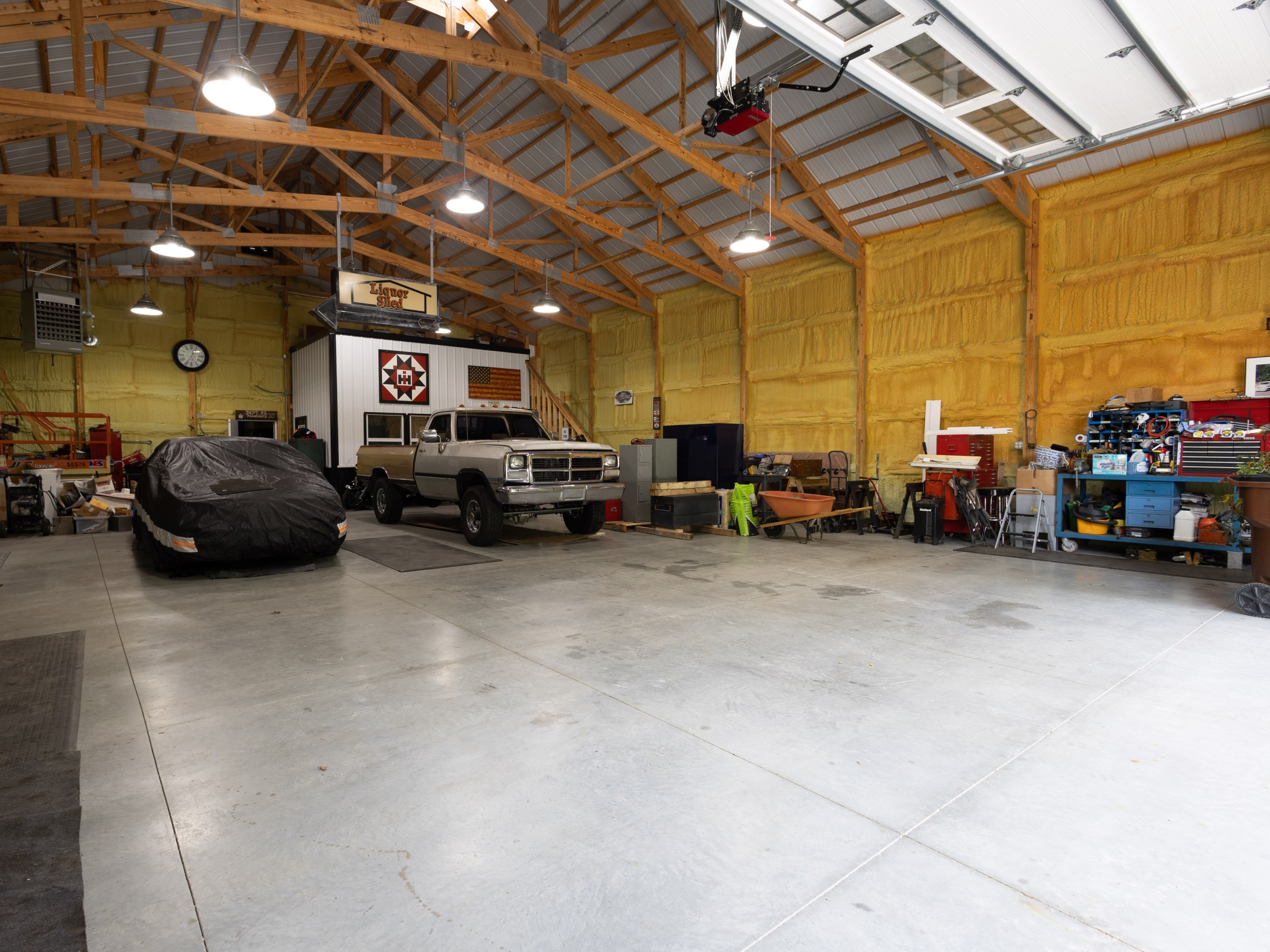 Interior of insulated post-frame garage with open-span storage space, concrete floor and exposed wood trusses