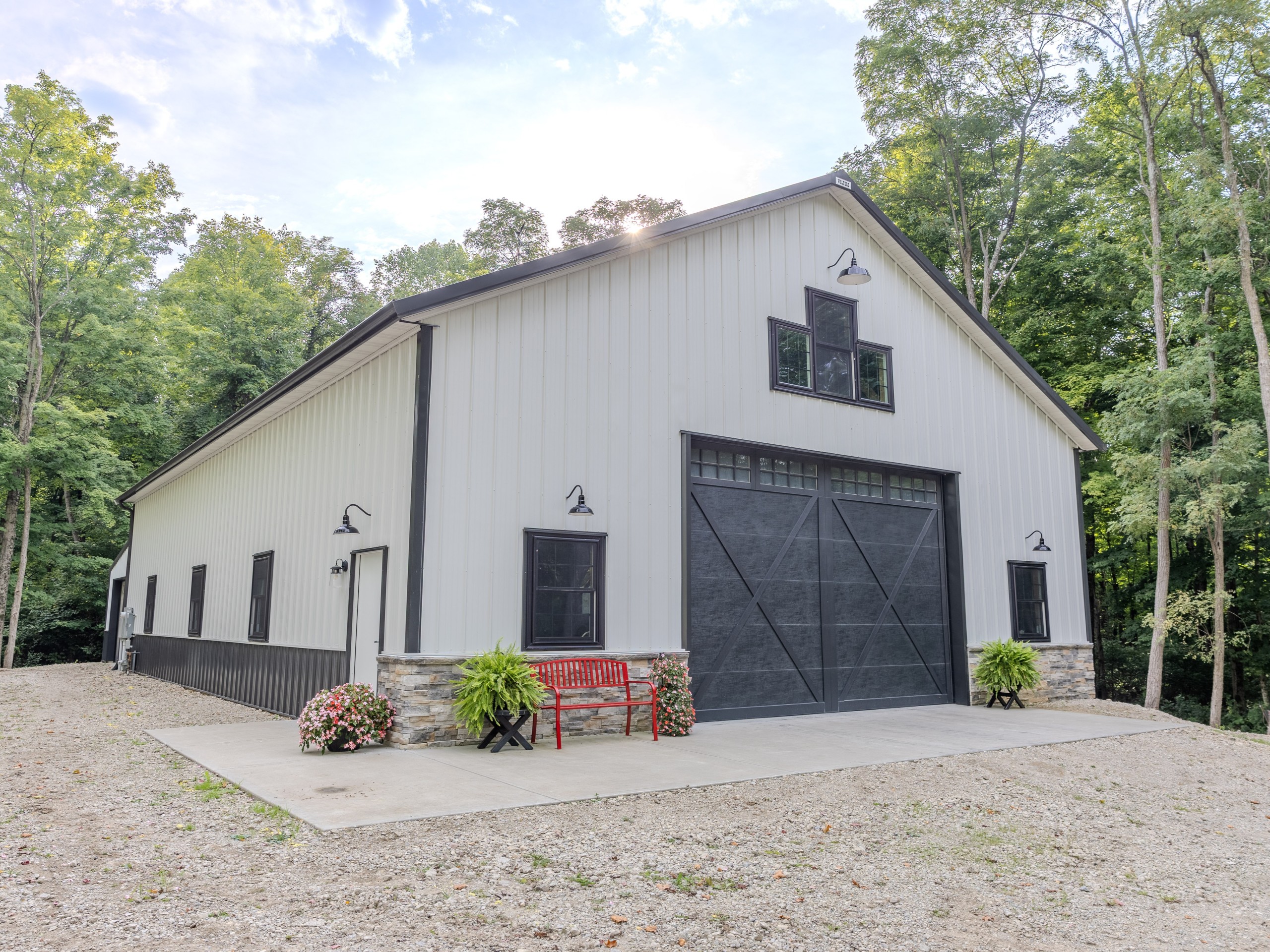 Custom post-frame garage with stone wainscot, black trim and side walk door