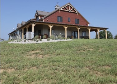 Luxury timber frame home with expansive views in Waddy, Kentucky, featuring a wraparound porch, decorative gable details, and custom post-frame residential design.