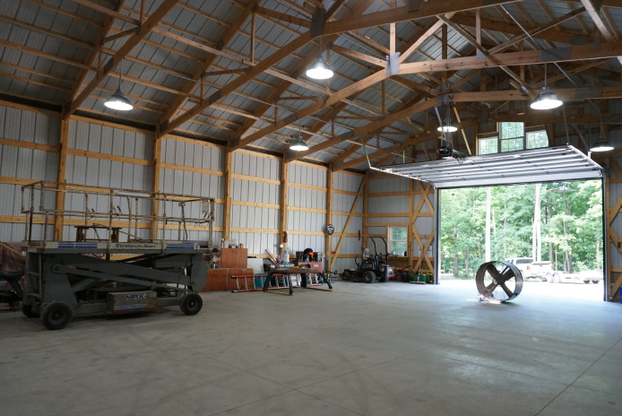 Close-up of stone wainscot base with white steel siding and black trim on post-frame building exterior