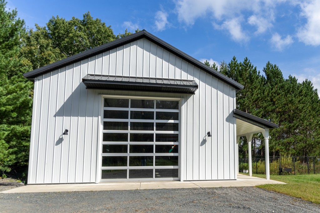 30′ x 48′ Pole Barn Garage Front 30' x 48' pole barn garage front with eyebrow overhang, white steel siding, black trim, and glass C.H.I. overhead door