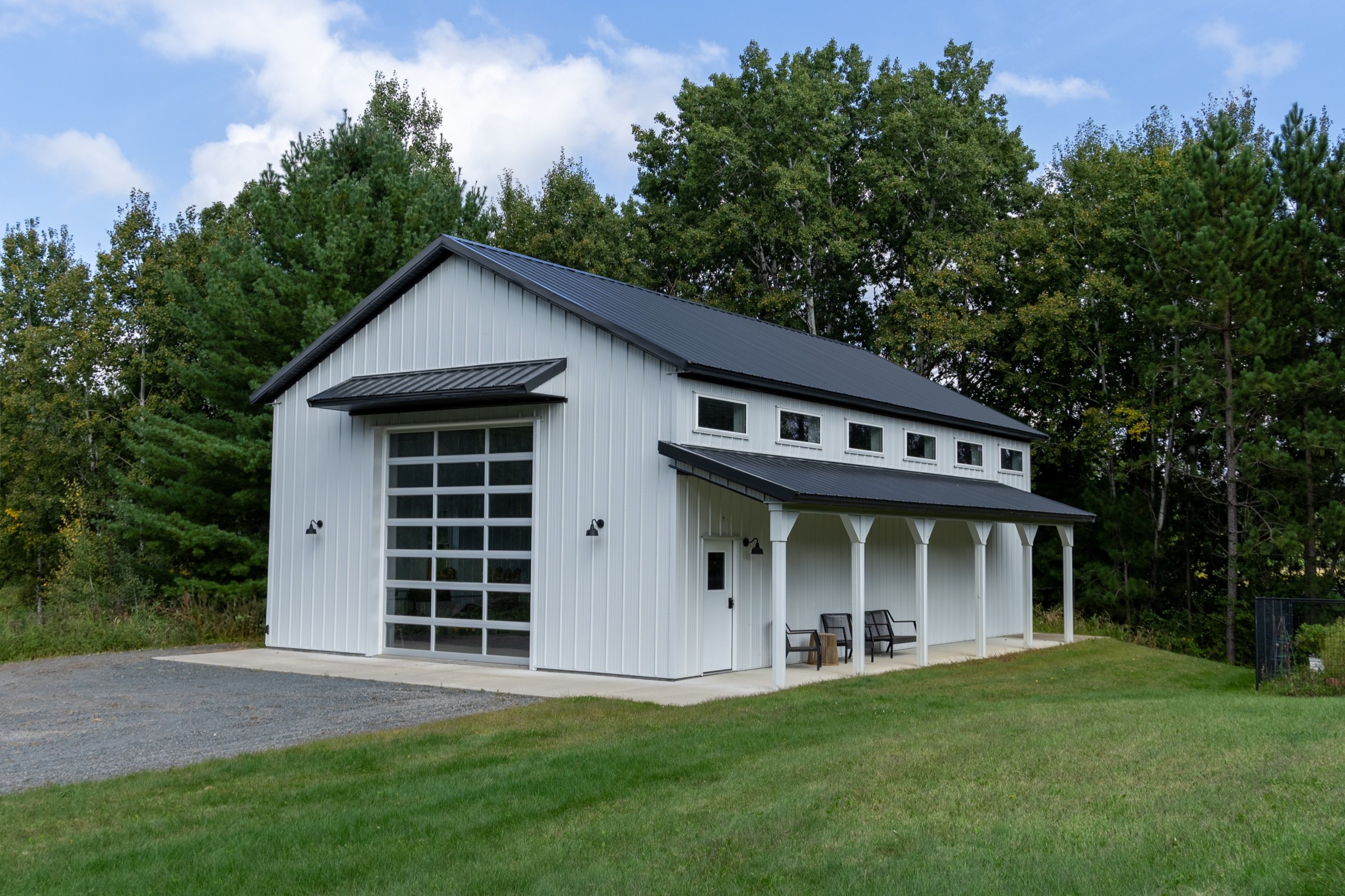 30' x 48' pole barn garage with side porch, white steel siding, black roof accents, eyebrow overhang, and C.H.I. overhead door