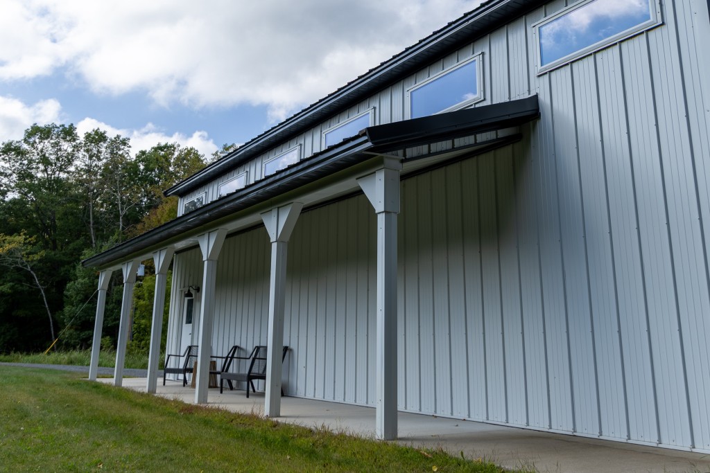 6′ x 40′ Side Porch 30' x 48' pole barn with rear angled view of the 6' x 40' side porch, white steel siding, and upper vinyl windows