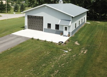 40x60 pole barn workshop with white steel siding, gray roof, and overhead garage door