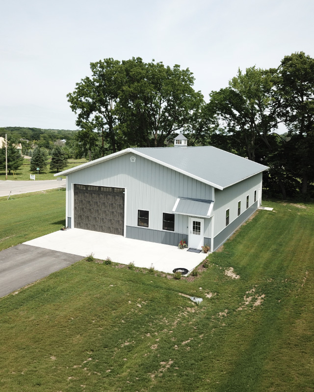 40x60 pole barn workshop with white steel siding, gray roof, and overhead garage door