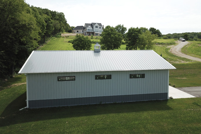 40x60 backyard pole barn garage with white steel siding, charcoal wainscot, and cupola