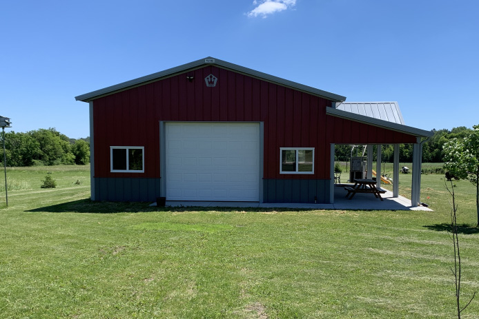 30x40 red pole barn garage with white overhead garage door covered patio and gray steel wainscot