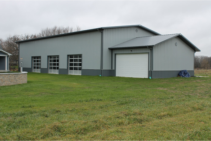 Clear-Span Indoor Sports Building | Basketball Court Facility | Walters Buildings Large indoor sports building with gray steel siding multiple overhead doors and clear-span post frame construction