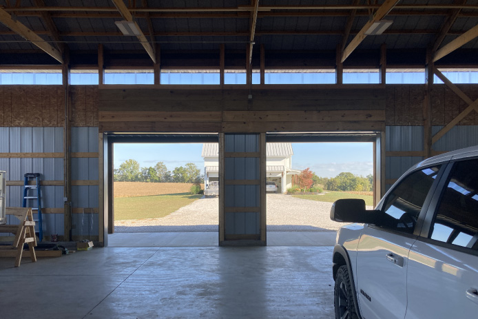 Interior of 40x64 post-frame pole barn with exposed wood trusses, vehicle storage, and open layout for equipment use