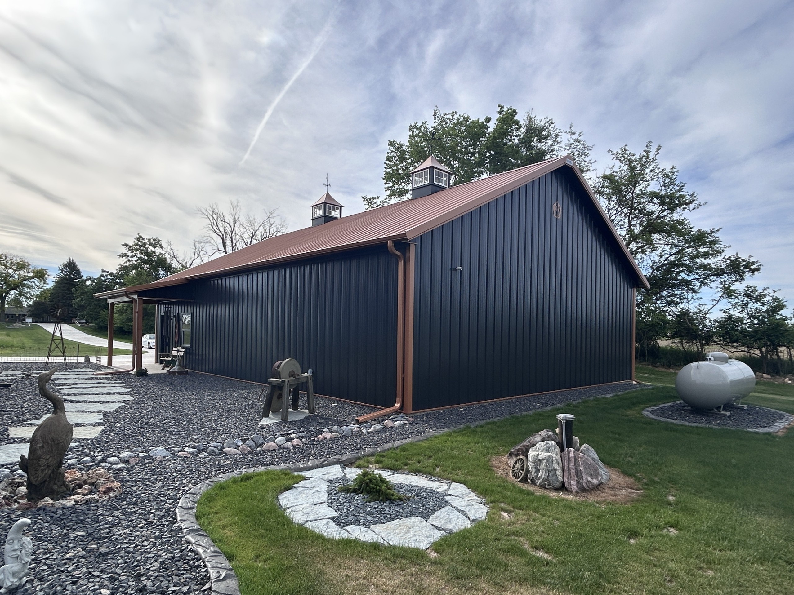Rear angle of custom post-frame metal garage with landscaped walkway and side porch by Walters Buildings