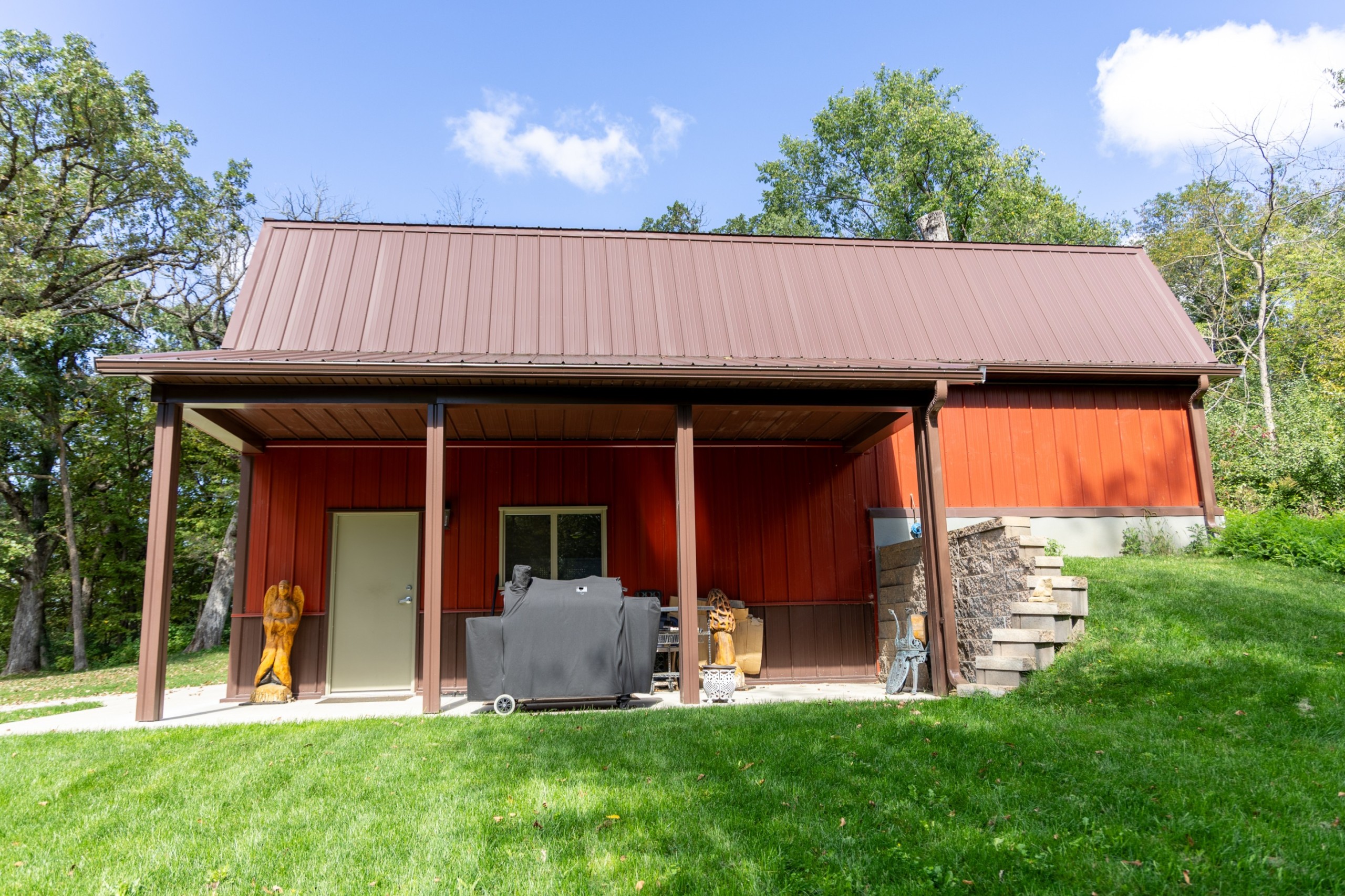 Side view of a two-story gambrel garage with a 24' x 8' porch, red steel siding, brown trim, and a thermal-break walk door