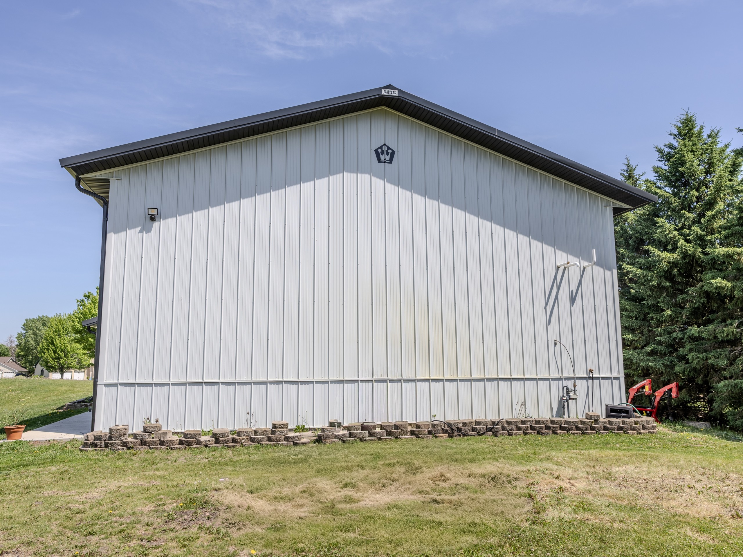 Rear view of a 36x50 post-frame storage building with white vertical steel siding and dark metal gable roof
