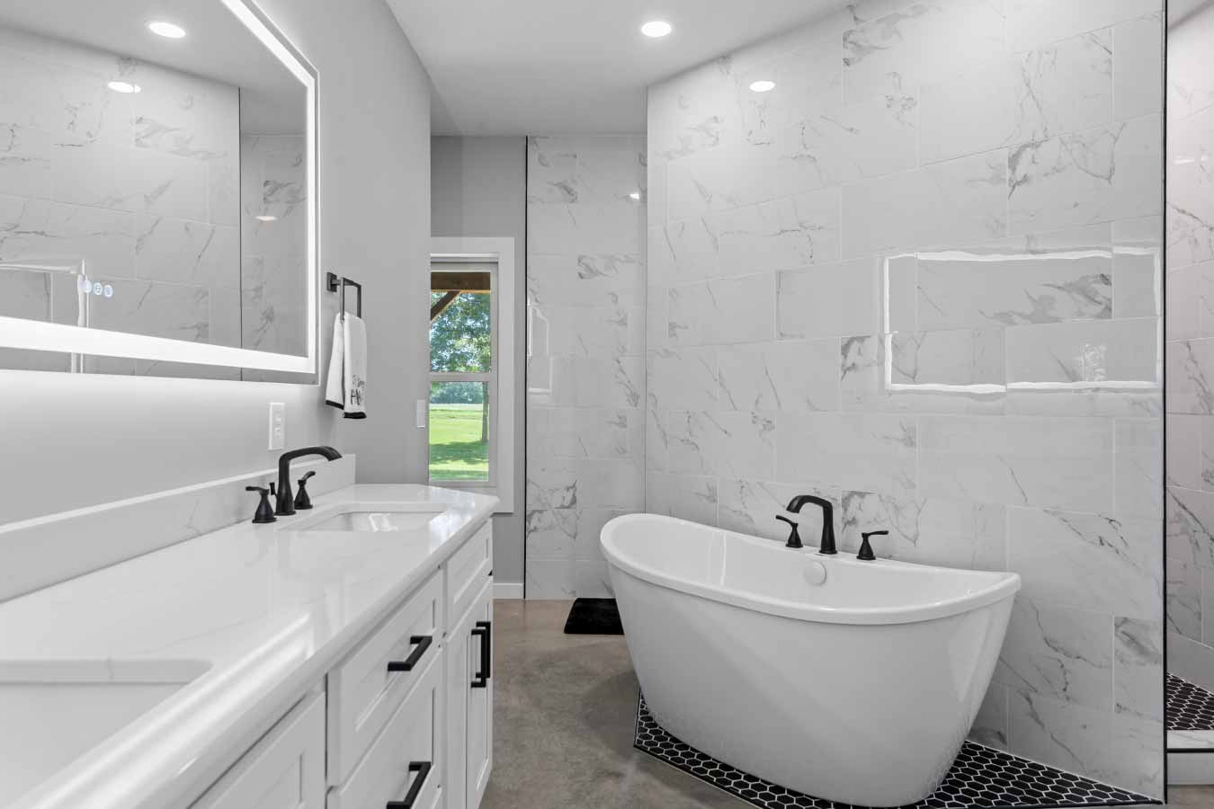 Luxurious master bathroom in a modern barndominium featuring a freestanding soaking tub, dual-sink vanity, and large tiled walk-in shower.