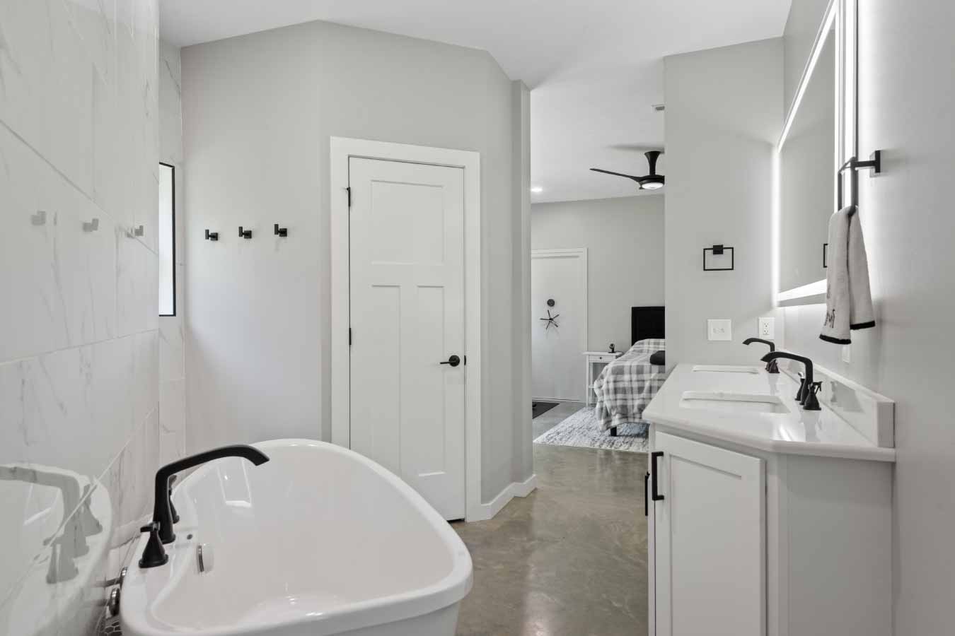 Freestanding soaking tub and dual vanity in the master bathroom of a barndominium.