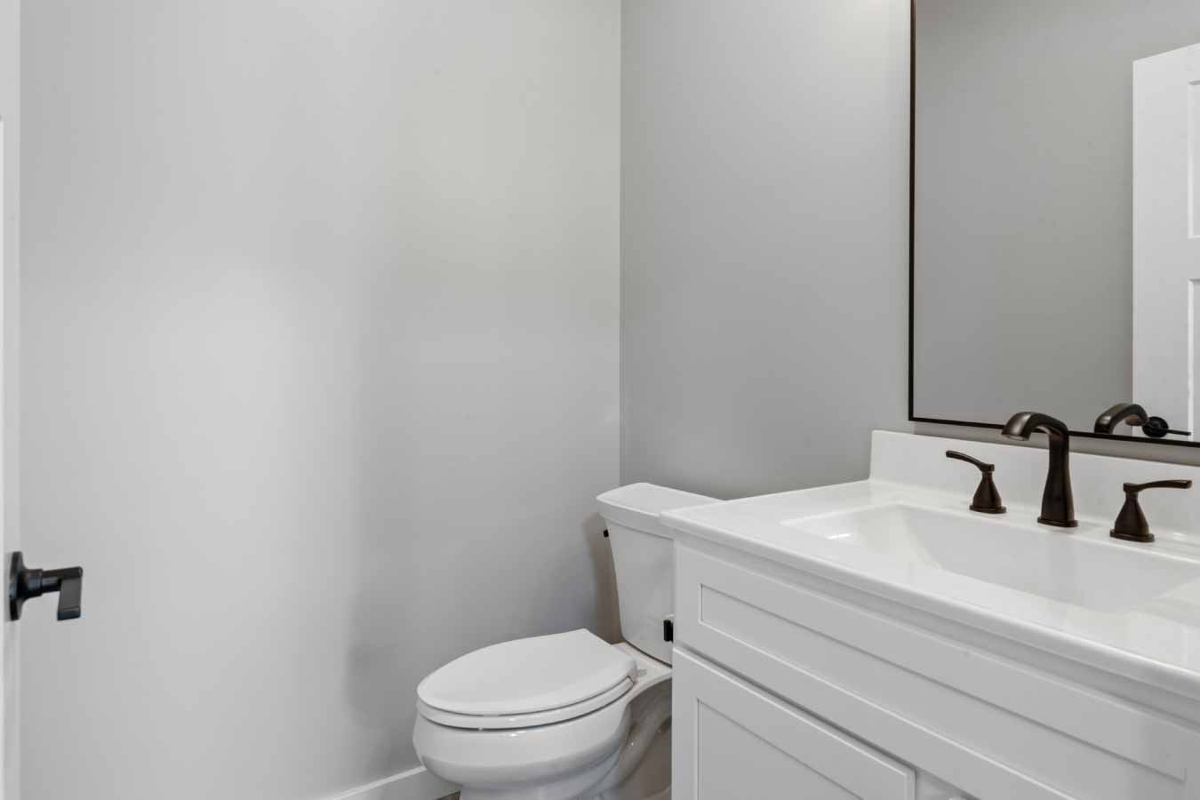 Half bathroom with white vanity and oil-rubbed bronze fixtures in a modern barndominium.