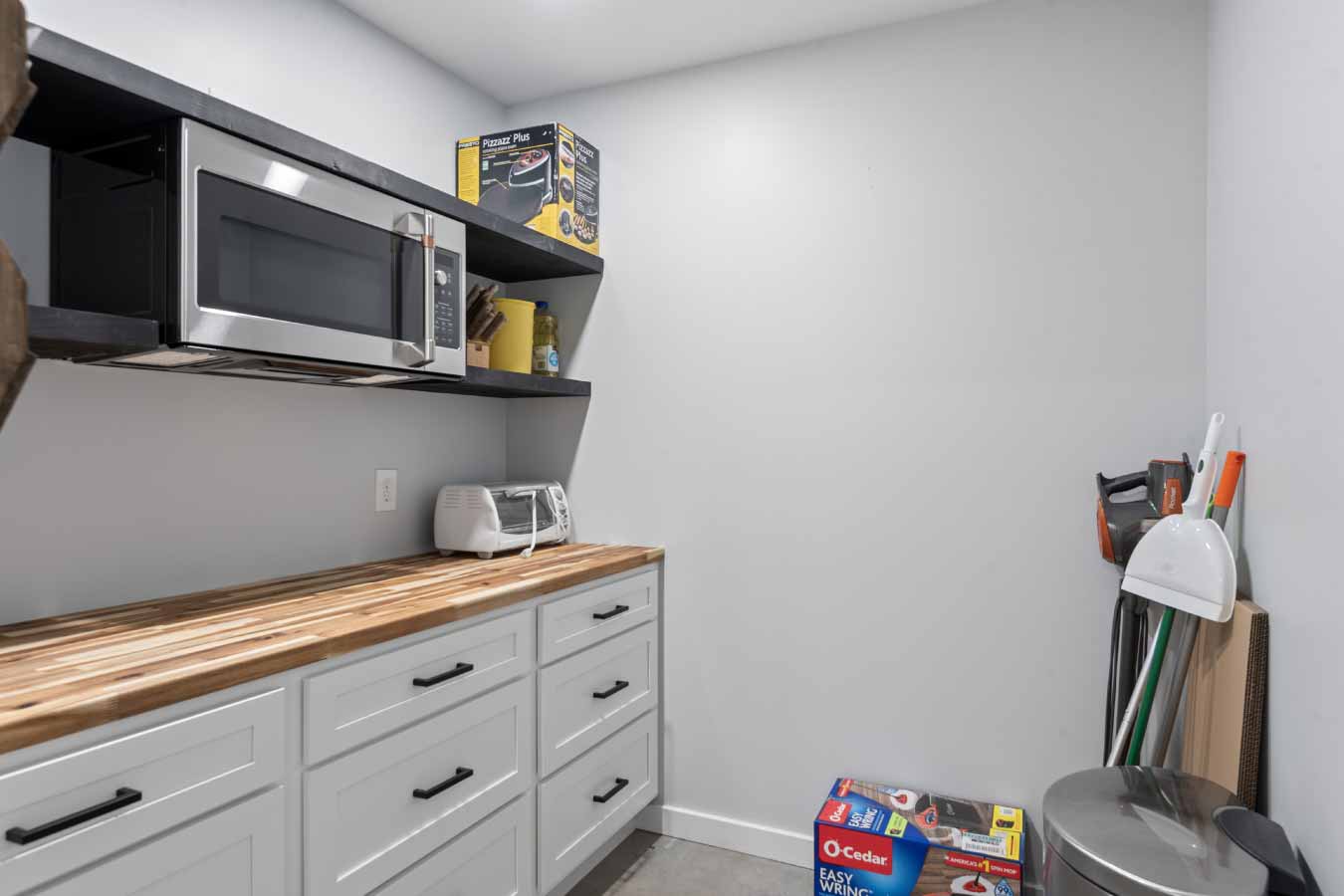 Hidden butler’s pantry with butcher block counters, white cabinetry, and open shelving in a modern barndominium.