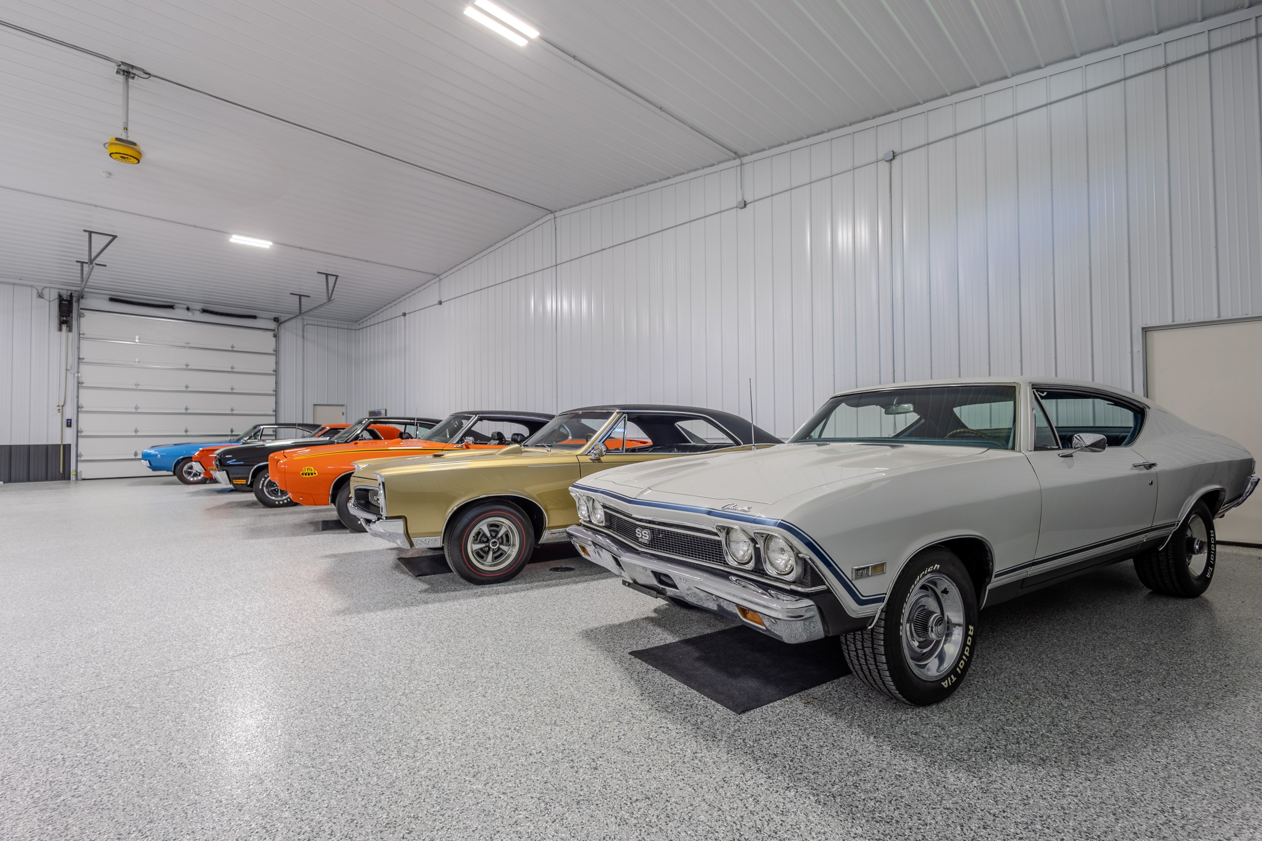 Classic American muscle cars displayed on decorative epoxy flooring inside a custom luxury car collector garage in Delavan, Wisconsin.