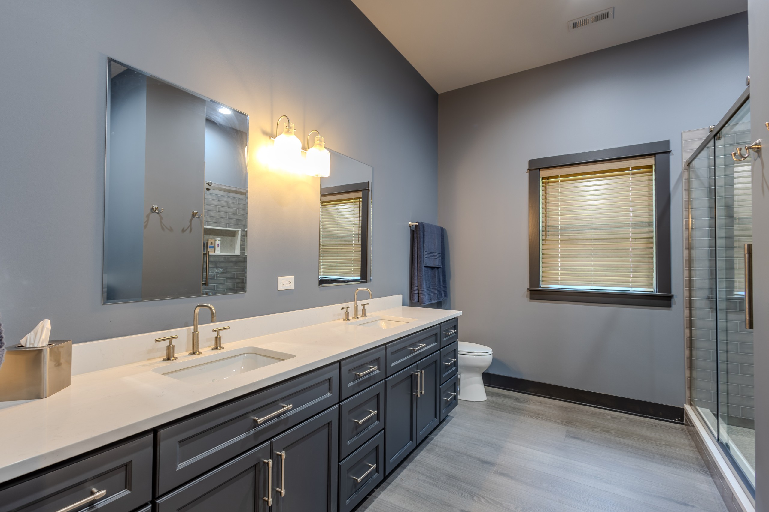 Finished bathroom in a luxury car collector garage clubhouse featuring a double-sink vanity, large mirrors and modern lighting.