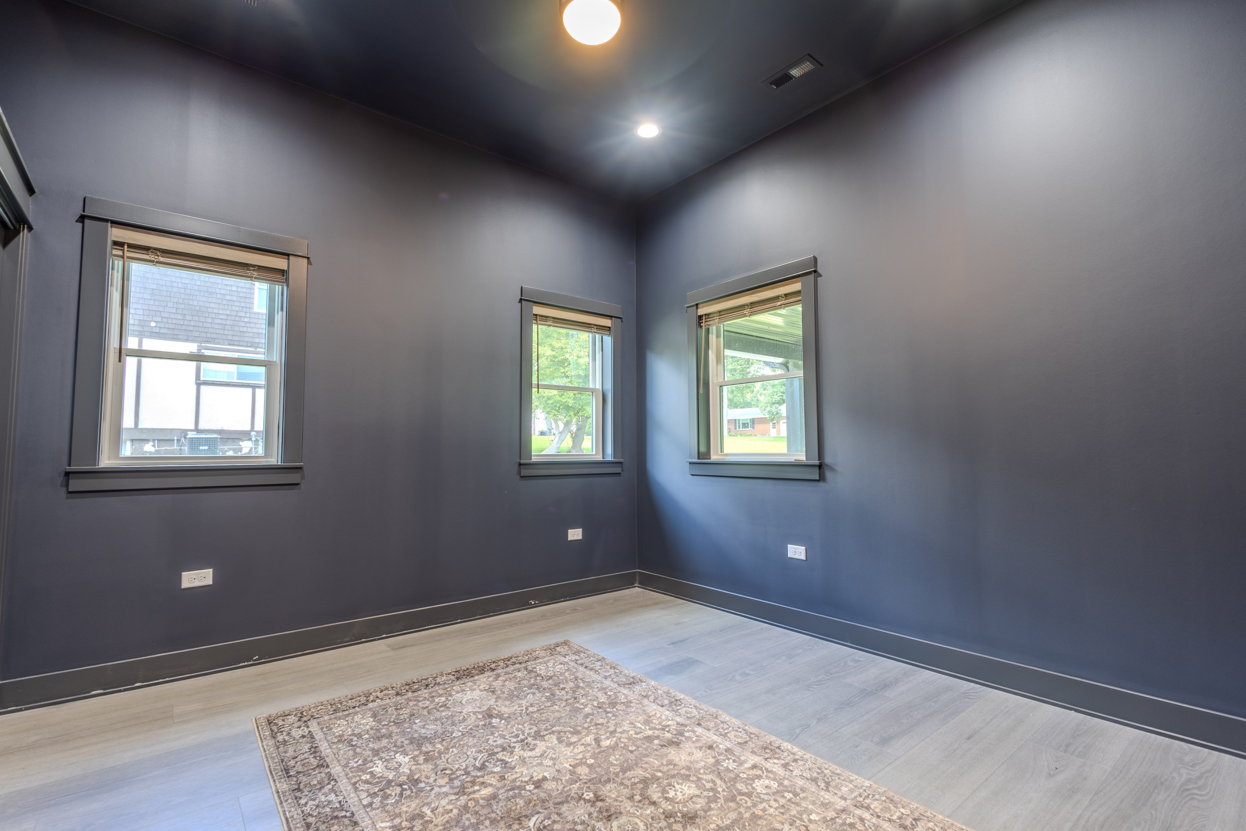 Finished spare room inside a luxury car collector garage clubhouse in Delavan, Wisconsin, featuring dark walls, windows and recessed lighting.